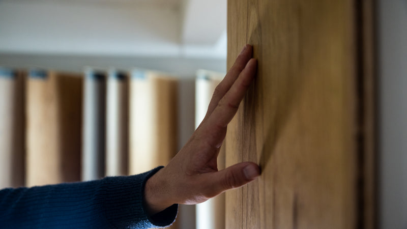 Hand mot trägolvsprov – materialkänsla och trästruktur