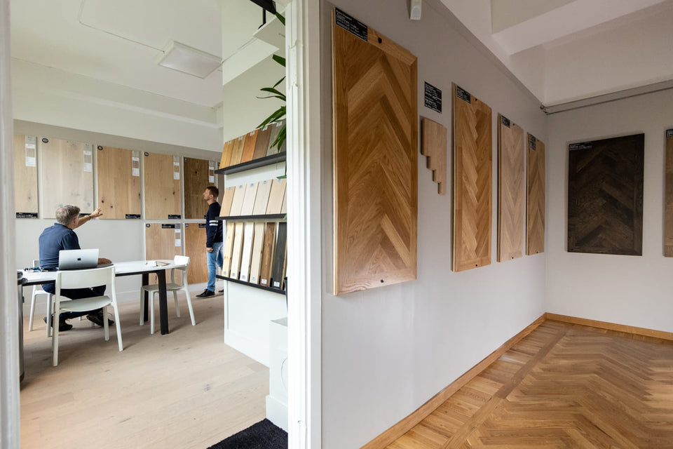 Övergångsvy mellan möteshörna och rum med väggmonterade golvprover.